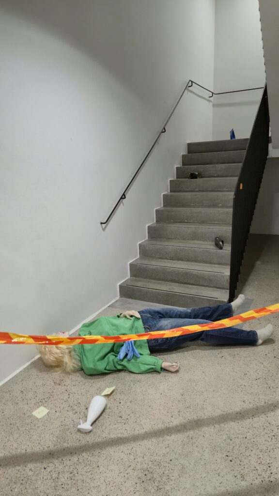 Rikostekninen tutkimus:
Näkymä rikospaikalta portaikon alaosasta: Portaikon alaosassa
makaa uhri, ympärillään todistusaineistoa sekä poliisin suojanauha. 