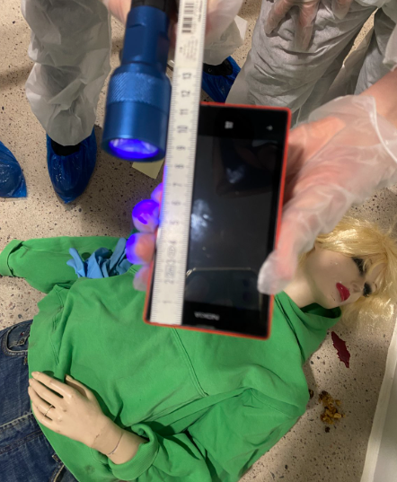 Rikostekninen tutkimus:
Kuvassa todistusaineistona toimiva puhelin ja mitta.